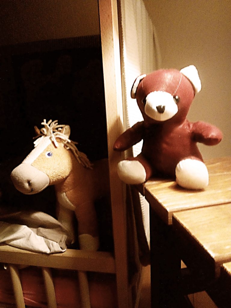 Stoffpferd und Stoffteddy lächeln in die Kamera.